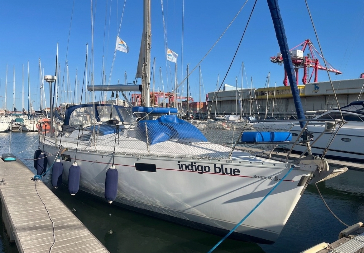 Sailboat 'Indigo Blue' moored at a Lisbon marina on a sunny day, revealing the safety netting, crisp hull marking, and well-maintained appearance.